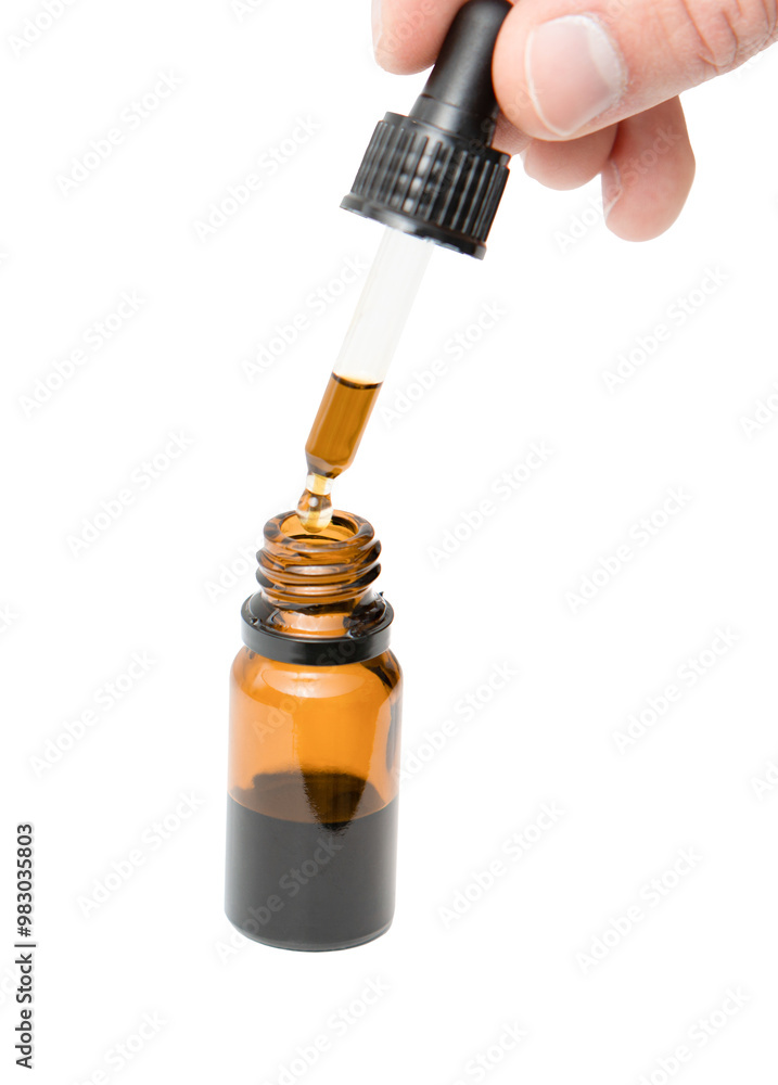 Hand dripping oil from a pipette in a glass bottle close-up isolated on white background Hand dripping oil from a pipette in a glass bottle close-up isolated on white background
