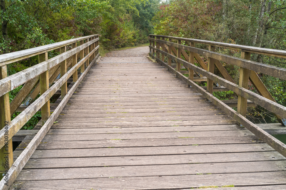 wide wooden bridge with railing over river wide wooden bridge with railing over river