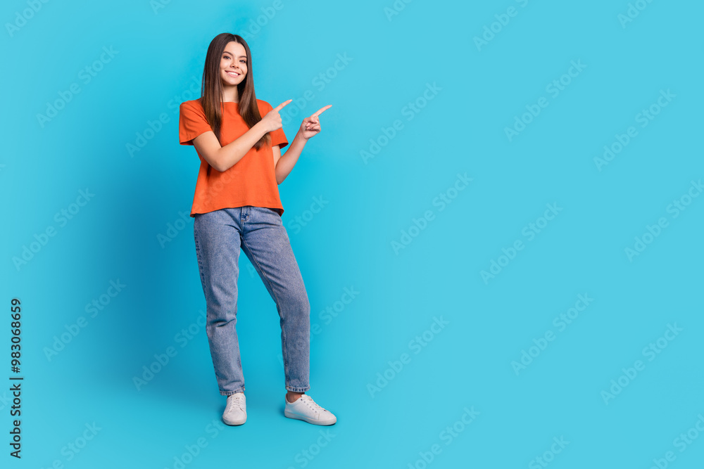 Full length photo of lovely teen lady point empty space dressed stylish orange garment isolated on blue color background Full length photo of lovely teen lady point empty space dressed stylish orange garment isolated on blue color background