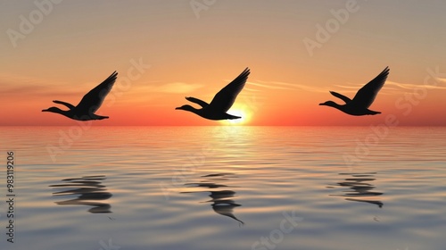 Three birds fly in formation across calm waters as the sun sets, casting warm hues of orange and pink in the sky while creating rippled reflections on the surface