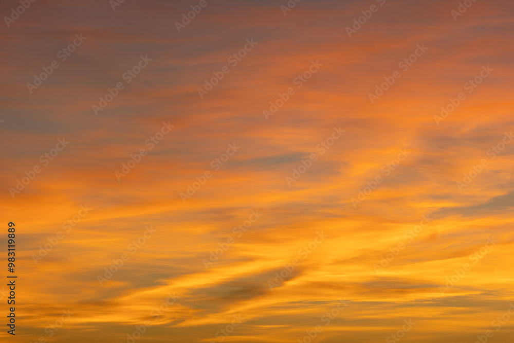 Obraz premium Glowing wispy clouds at sunset transition to evening, casting colorful rays in a serene sky. Perfect for vibrant and calming views
