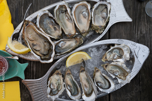 Eating of fresh live oysters with citron at farm cafe in oyster-farming village, Arcachon bay, Gujan-Mestras port, Bordeaux, France in sunny day, huge oyster photo