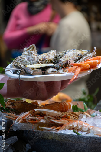 Assortment of fresh daily catch of prawns, seashells, molluscs on ice on fish market in Brittany, France, English translation: differens French names of seafood photo