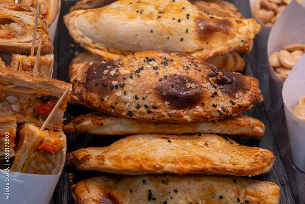 Traditional Spanish and Latin American pies empanadas with different fillings, at farmer's market in bakery with tuna fish, sweet onion, goat cheese, bacon Traditional Spanish and Latin American pies empanadas with different fillings, at farmer's market in bakery with tuna fish, sweet onion, goat cheese, bacon