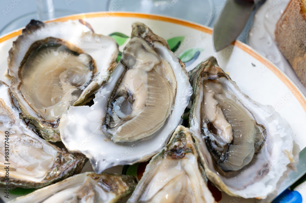 Plate with fresh live oysters with citron, bread, butter and white wine served at restaurant in oyster-farming village, Arcachon bay, Gujan-Mestras port, France Plate with fresh live oysters with citron, bread, butter and white wine served at restaurant in oyster-farming village, Arcachon bay, Gujan-Mestras port, France