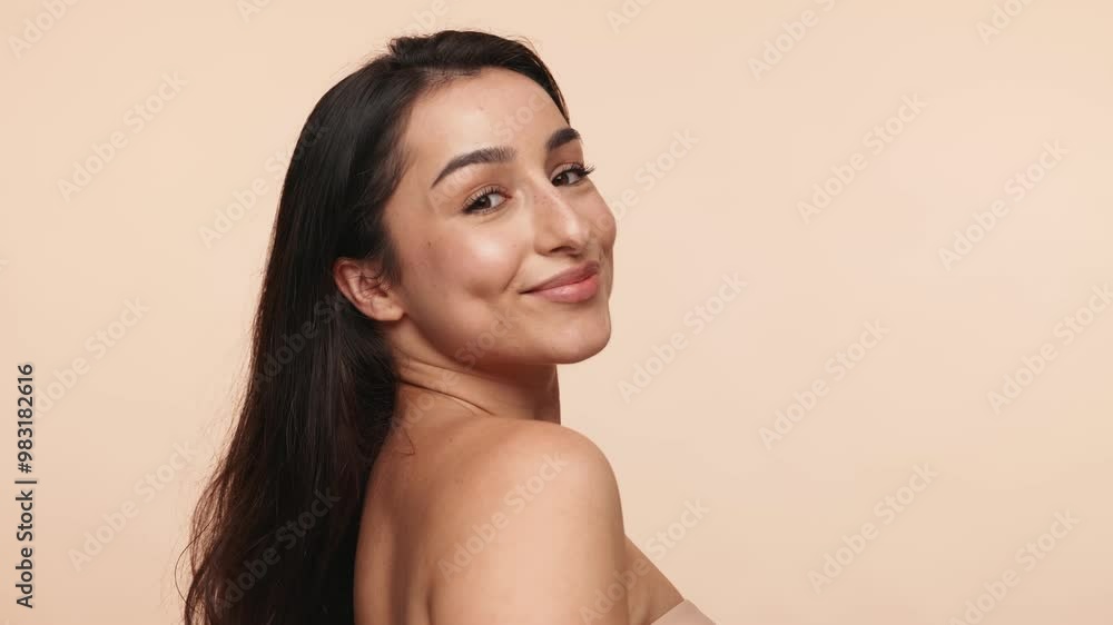 Studio shot of a serene brunette woman applying makeup with a brush, side profile to facing the camera, isolated on a neutral background. Studio shot of a serene brunette woman applying makeup with a brush, side profile to facing the camera, isolated on a neutral background.