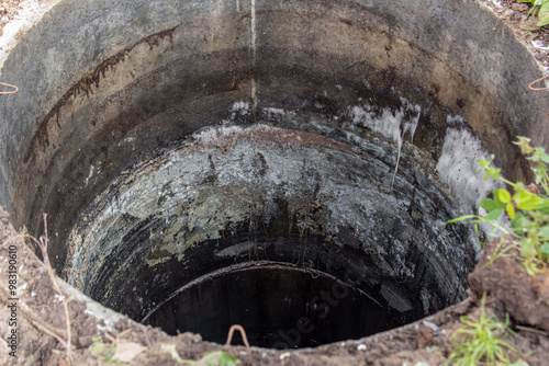 Dirty concrete well. White mold and limescale on the walls of the sewer. Silt in the cesspool photo