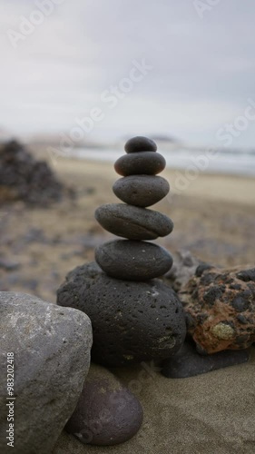 Stacked stones on famara beach in lanzarote, canary islands, during daylight, showing a serene, outdoor setting with blurred background for tranquility. photo