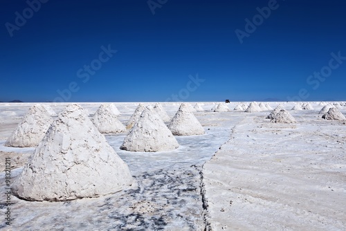 Salt pyramids on a vast white salt flat under a clear blue sky.