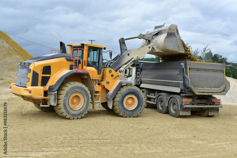 Yellow excavator loading stones in a truck Yellow excavator loading stones in a truck