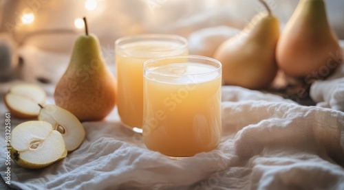Refreshing pear juice served in glasses alongside fresh pears on a beige line...