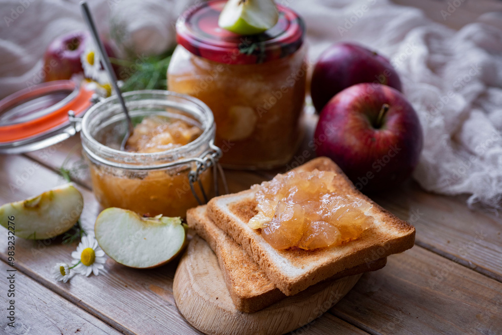 Apple jam in a jar on a wooden table. Apple jam on toast. Sandwich with apple marmalade. Close-up Apple jam in a jar on a wooden table. Apple jam on toast. Sandwich with apple marmalade. Close-up