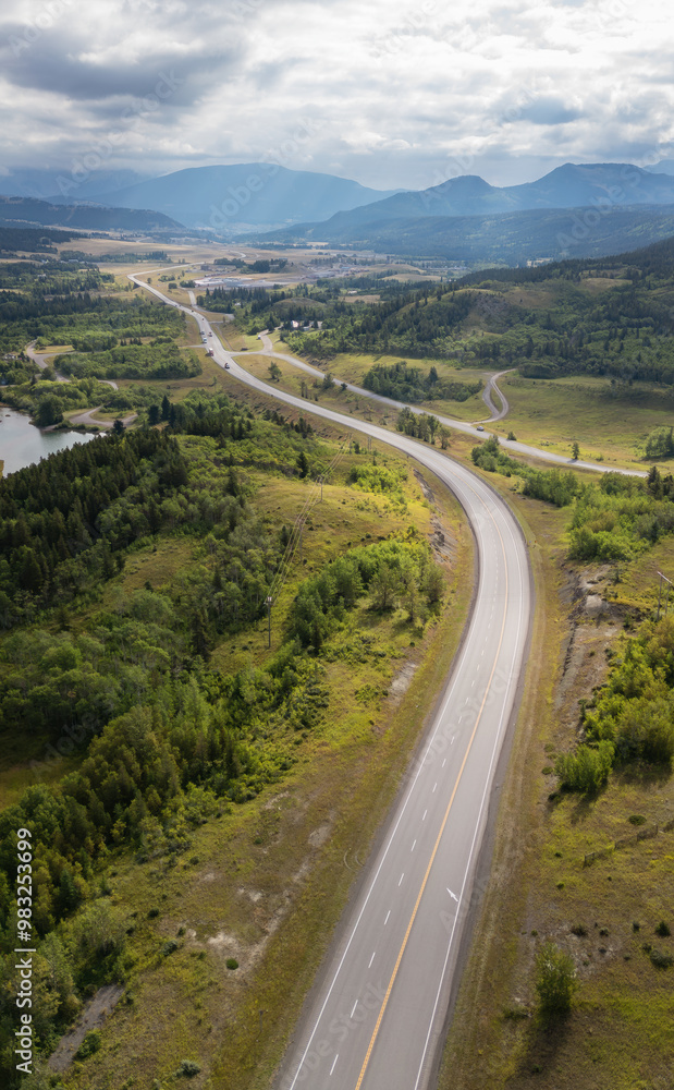 Scenic Aerial View of Winding Highway through Lush Green Landscape in Alberta, Canada under Cloudy Sky Scenic Aerial View of Winding Highway through Lush Green Landscape in Alberta, Canada under Cloudy Sky