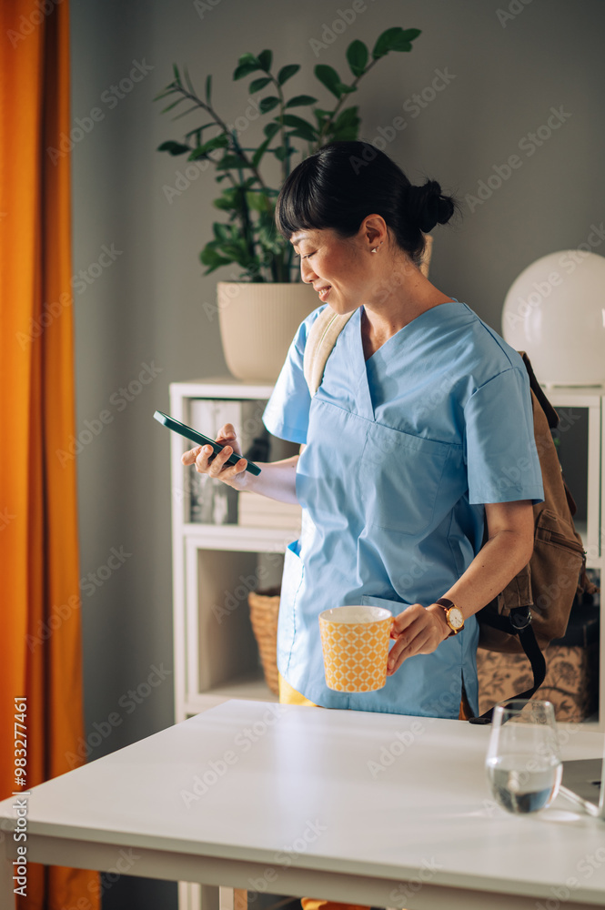 Asian woman healthcare professional with a brown backpack checking their phone Asian woman healthcare professional with a brown backpack checking their phone