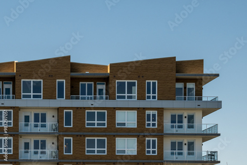 St. John's, Newfoundland, Canada-September 1, 2024: A new apartment complex. The wall has beige modern metal paneling. Each unit has a glass balcony with a glass patio door. The condo units are empty.