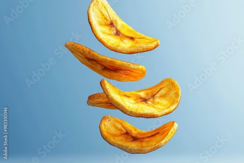 Golden Banana Chips Falling Against a Blue Background photo