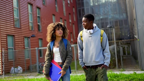 Two male and female multiethnic students reunited backing to university standing chatting outdoors photo