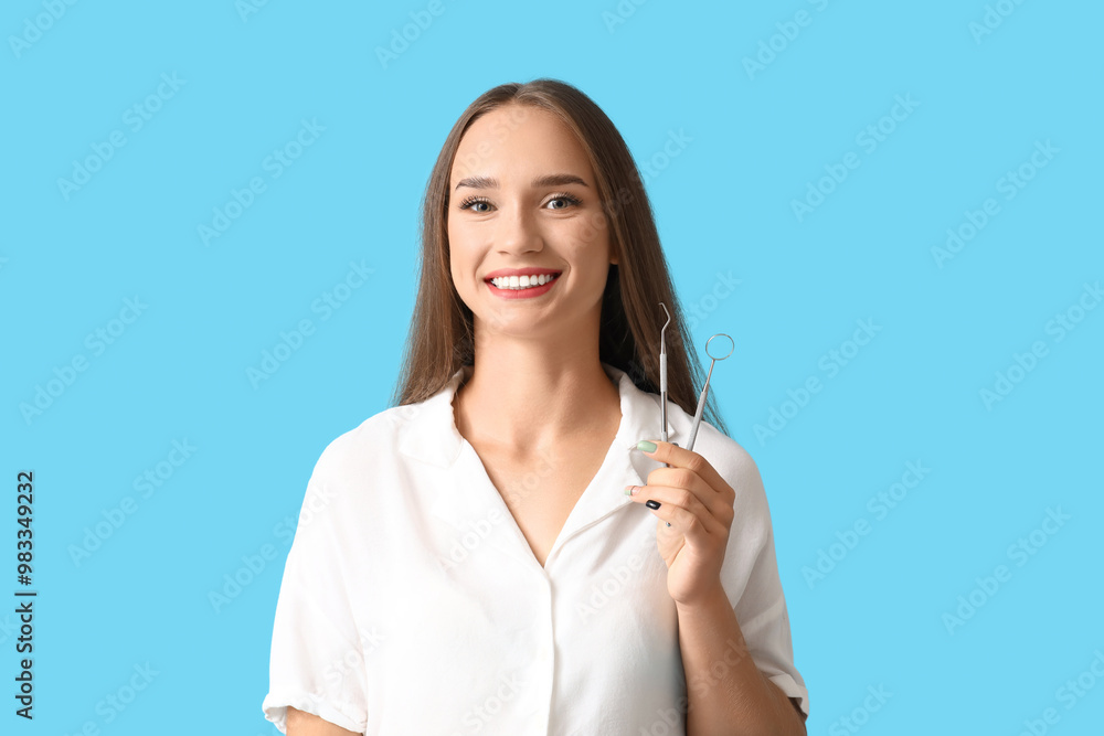 Smiling young woman with dental tools on blue background Smiling young woman with dental tools on blue background