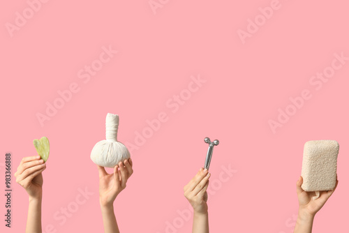 Female hands with facial massage tool, herbal massage bag and bath sponge on pink background