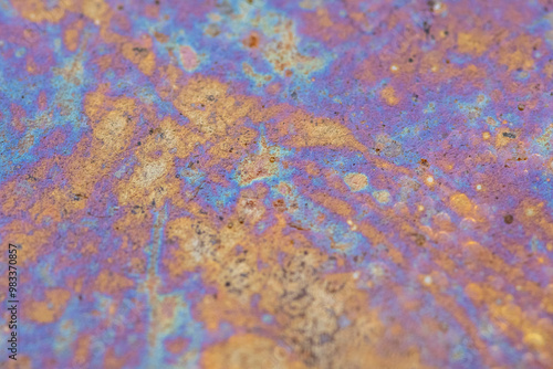 Colorful oil slick patterns in a small water puddle