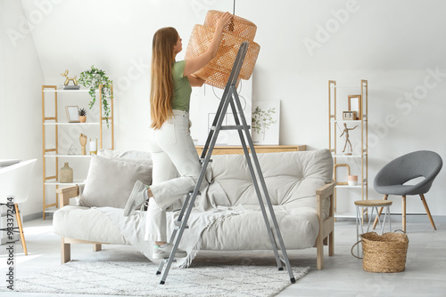 Young woman screwing light ...