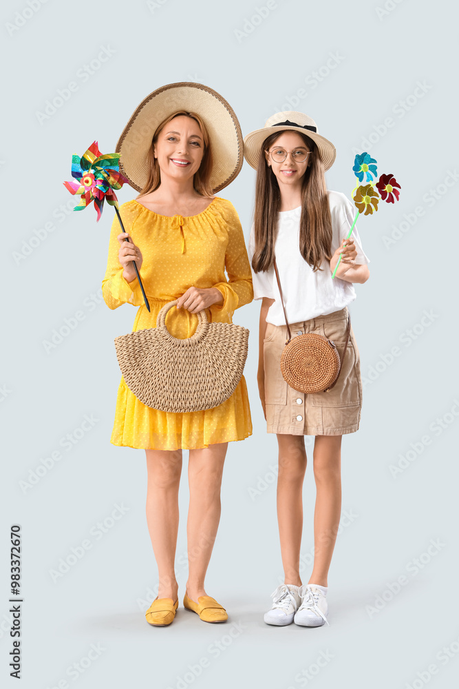 Teenage girl and her mother with toy windmills on light background Teenage girl and her mother with toy windmills on light background