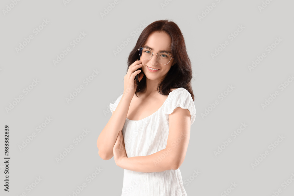 Young woman talking by mobile phone on light background Young woman talking by mobile phone on light background