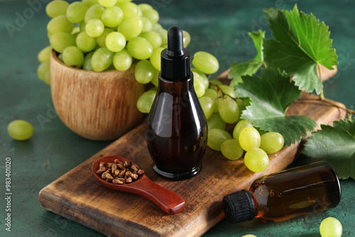 Bottles of cosmetic grape seed oil on green background