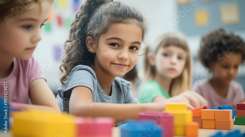 A joyful girl engages with colorful building blocks in a bright classroom, promoting creativity and teamwork among friends.
