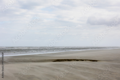 Landscape view of wide and long sand beach on the Dutch Wadden sea under cloudy sky, Schiermonnikoog is a municipality and national park in the Northern Netherlands and one of the West Frisian Islands photo