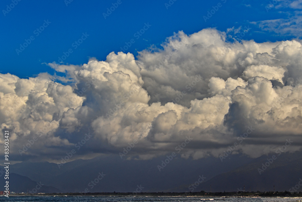 view of the horizon from Indaia beach, with a large white cumulus cloud covering the Serra do Mar mountains. view of the horizon from Indaia beach, with a large white cumulus cloud covering the Serra do Mar mountains.