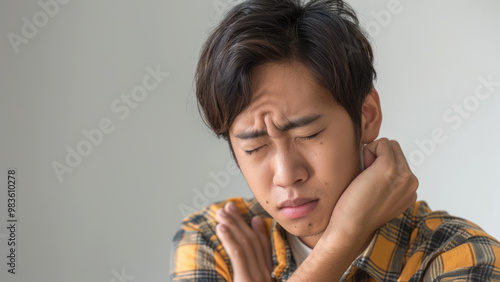 Young man with neck pain holding his neck in discomfort.