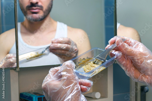 Fotografía Hombre mezclando tinte para teñir su barba y bigote, usando cepillo y guantes de plástico