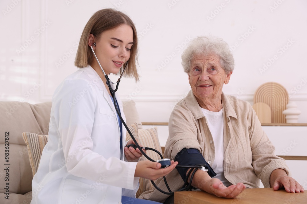 Doctor measuring patient's blood pressure at wooden table indoors Doctor measuring patient's blood pressure at wooden table indoors