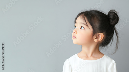 Side view of Japanese little girl wearing white dress isolated on gray