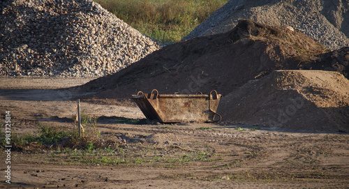 Rusty skip bin in a construction site with piles of gravel and earth, symbolizing industrial work