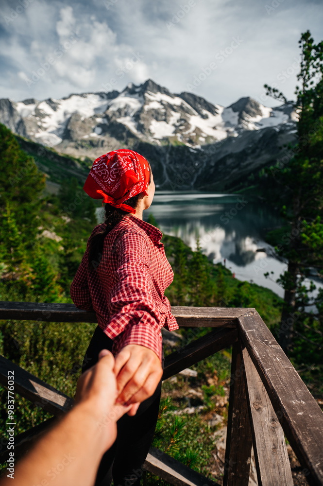 Naklejka premium A guy holds a girl's hand looking at the snow-capped mountains on the Multin lake