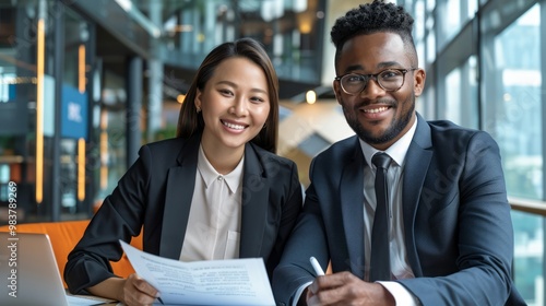 African-American and Asian business partners in a modern office setting, reviewing and signing important documents, with a focus on global collaboration and diversity