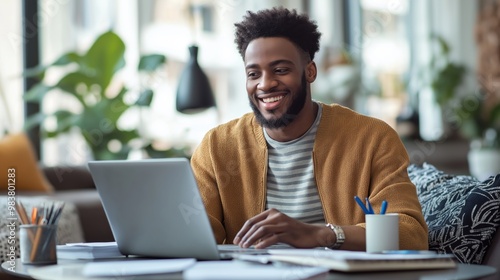  A cheerful man smiles while working on his laptop in a modern office