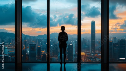 A person standing at a large window, looking out at a city skyline, thinking about the future and career goals