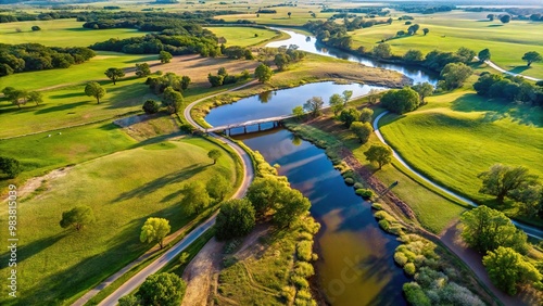 Aerial view of a winding creek and bridge passing through ranch land