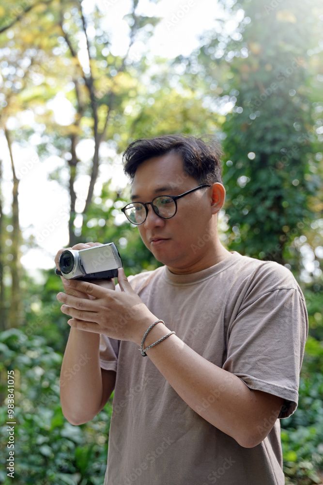 Young Asian man behind the camera directs and shoots the scene, video production enthusiast uses digital camcorder to capture footage. Young Asian man behind the camera directs and shoots the scene, video production enthusiast uses digital camcorder to capture footage.