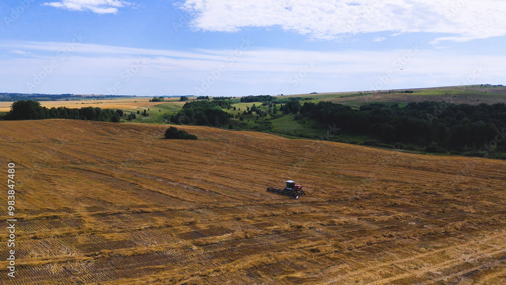 Obraz premium a combine harvester in a wheat field performs harvesting operations