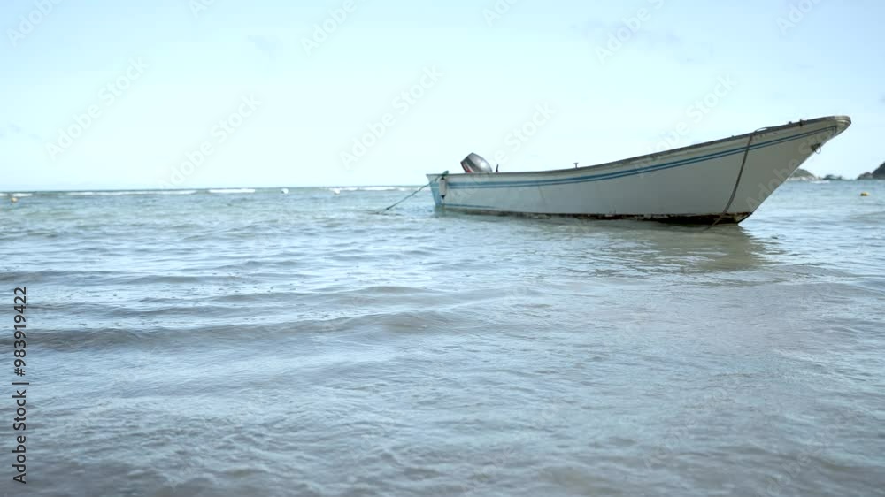 Empty boat moored in shallow waters, viewed from a low angle, with a serene sea and clear sky. It evokes tranquility and solitude. Slow Motion Shot Empty boat moored in shallow waters, viewed from a low angle, with a serene sea and clear sky. It evokes tranquility and solitude. Slow Motion Shot
