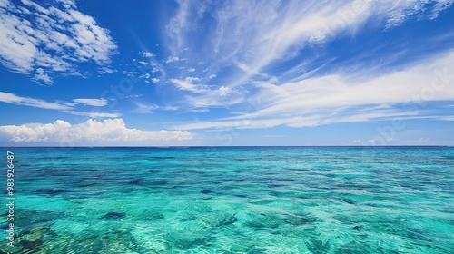 A beautiful scene of the blue ocean against the blue sky background. The ocean stretches out as far as the eye can see, with its surface glistening in the sunlight