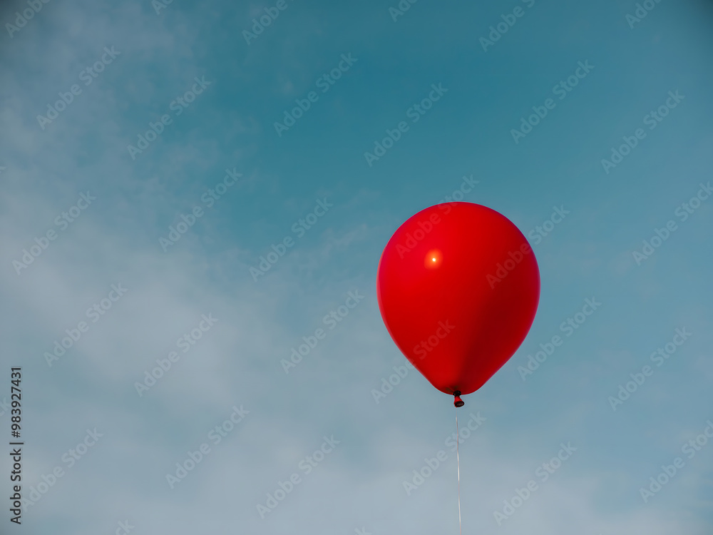 Obraz premium A single red balloon floats in a clear blue sky