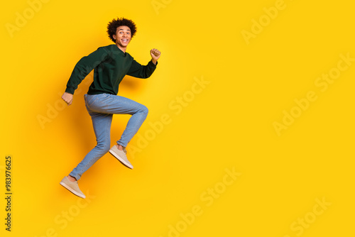 Full size photo of nice young man jump run empty space wear pullover isolated on yellow color background