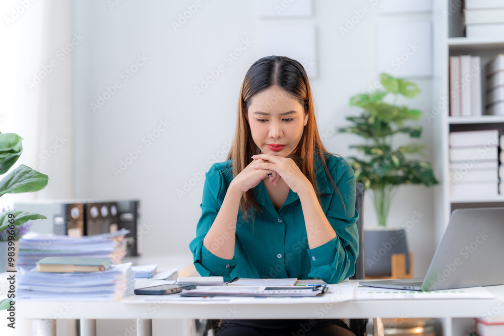 Focused Concentration: A serious businesswoman thoughtfully examines documents at her desk, surrounded by a mountain of paperwork, reflecting the demands and complexities of modern business. Focused Concentration: A serious businesswoman thoughtfully examines documents at her desk, surrounded by a mountain of paperwork, reflecting the demands and complexities of modern business.