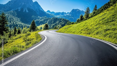 Winding asphalt road in the Austrian Alps surrounded by lush greenery and towering mountains under a clear blue sky