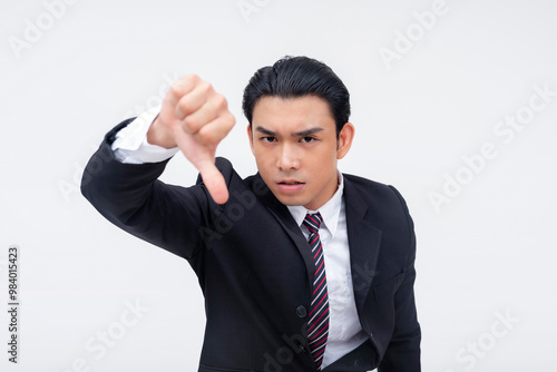 A young asian business executive vehemently giving a thumbs down sign, against certain policies and rules. Isolated on a white background. photo